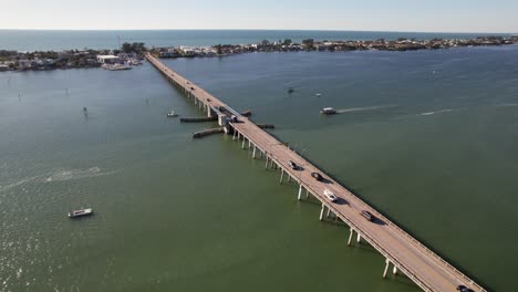 drone clip over large river with cars driving over long bridge and open sea in the background, on a warm summer day