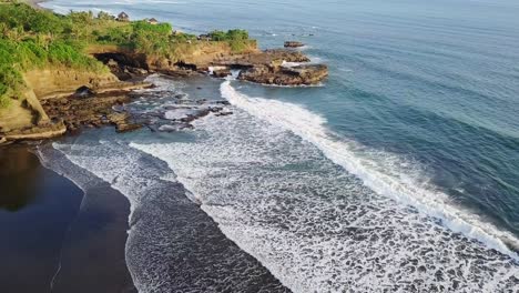 Luftaufnahme-Eines-Strandes-Mit-Wellen,-Die-Das-Ufer-Und-Die-Grüne-Klippe-Erreichen