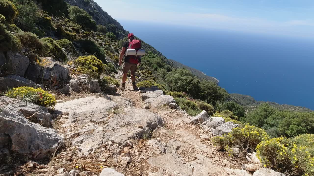 hombre con mochila caminando en el borde del acantilado de una alta montaña rocosa en lycian way, turquía