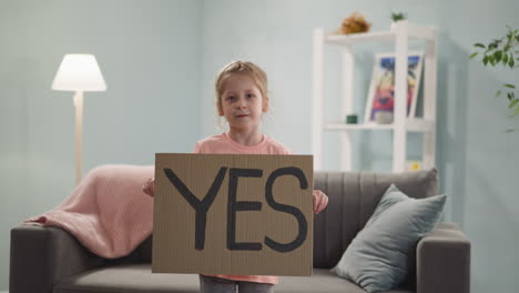 joyful, contented smiling little girl stands and holds poster