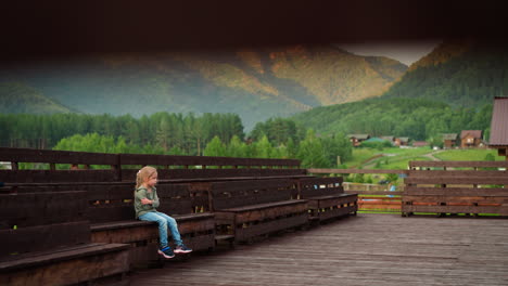 unhappy girl embraces herself sitting alone on wet bench