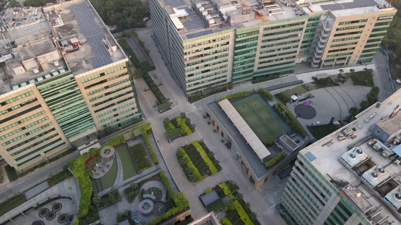 Sweeping drone shots of a sleek business park in Gurgaon, Haryana—glass skyscrapers, landscaped greenery, and urban infrastructure reflecting India’s growing global corporate presence