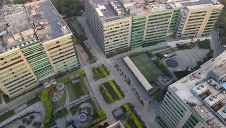 sweeping drone shots of a sleek business park in gurgaon, haryana—glass skyscrapers, landscaped greenery, and urban infrastructure reflecting india’s growing global corporate presence