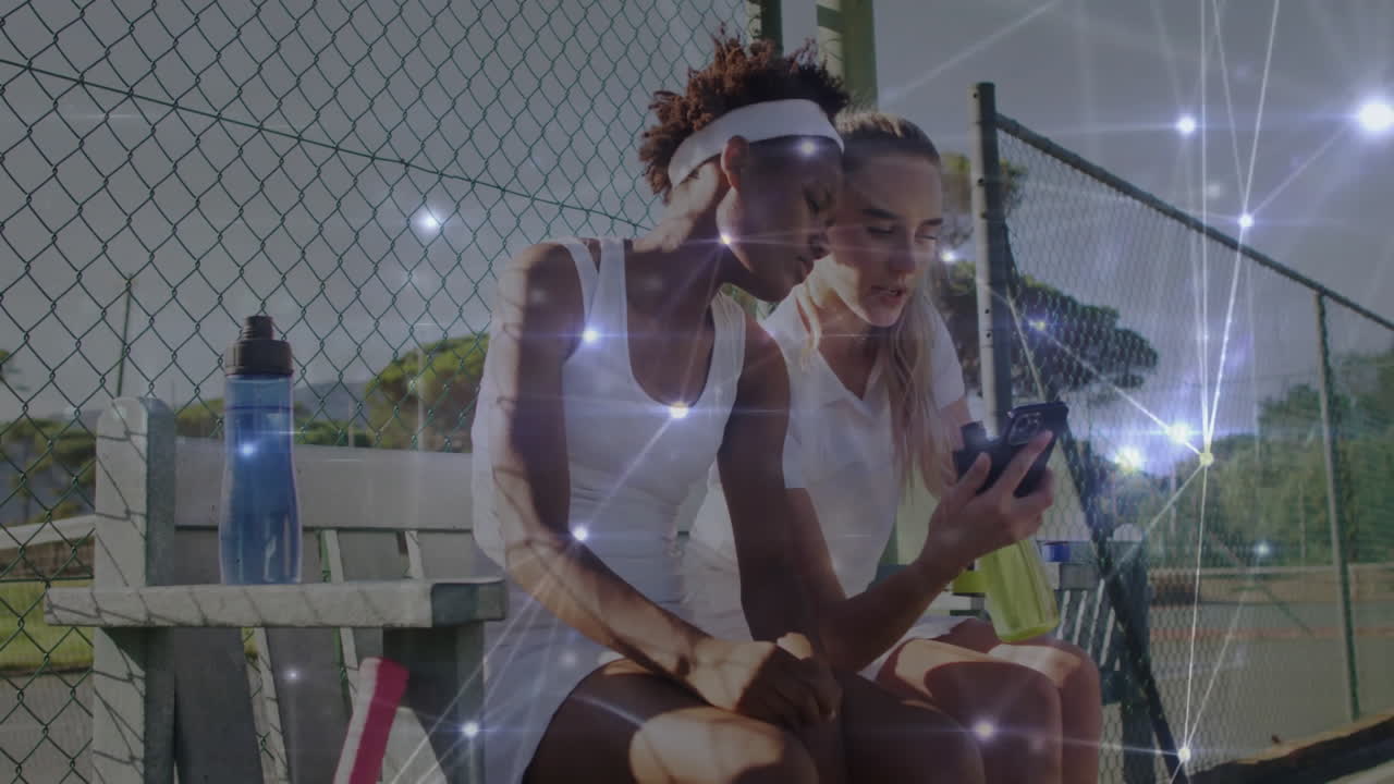 women sitting on wooden bench beside tennis court, showing smartphone with animated health chart