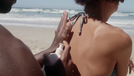 hombre aplicando protector solar en los hombros de la mujer en la playa 4k