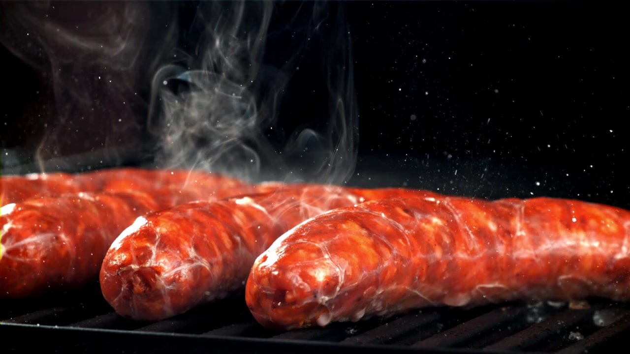Salsicce Deliziose che Sfrigolano su una Griglia Calda con Fumo che Sale