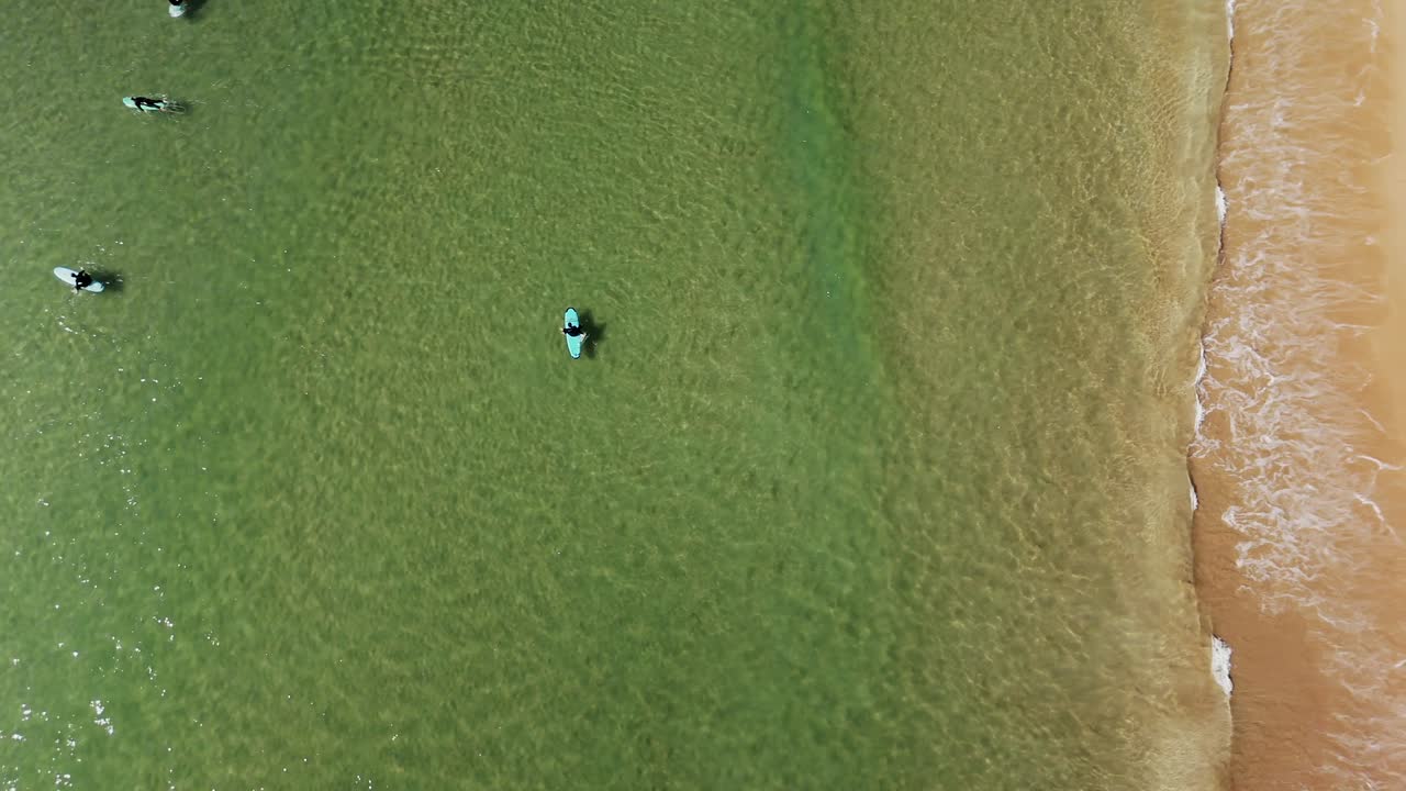 Aerial view of a beach with surfers and waves