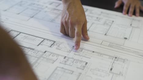 an architect traces the outline of a house plan, guiding us through the blueprint of a dream home with his finger