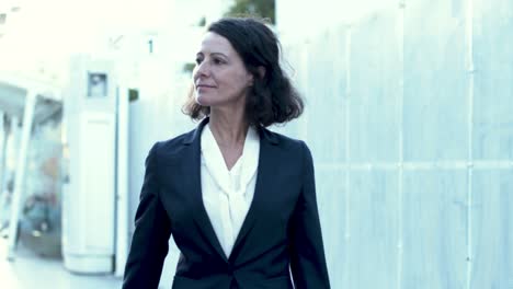 beautiful smiling businesswoman walking on street