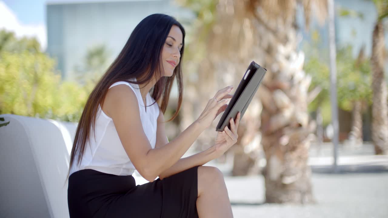 mujer joven sonriente que usa su tableta al aire libre