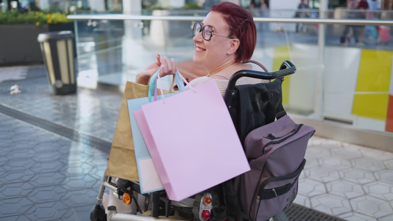Donna felice su sedia a rotelle motorizzata con borse della spesa
