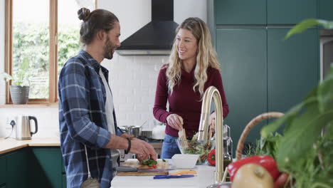 Happy-diverse-couple-preparing-dinner-in-kitchen-using-tablet-at-home,-in-slow-motion