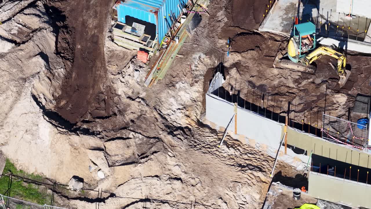 Drone footage captures construction workers and machinery at a building site in Gold Coast, Australia, under bright daylight
