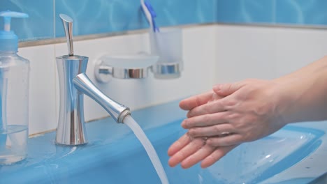 The-girl-washes-her-hands,-using-liquid-soap,-in-a-beautiful-blue-sink