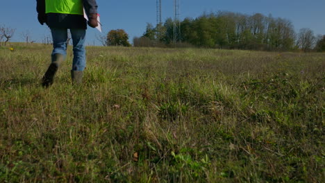 male engineer walking on the grass towards the two cellular towers, low angle tilting shot revealing