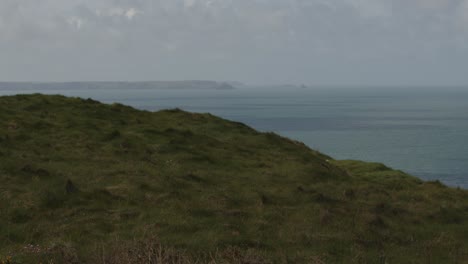 fotografía panorámica del mar y los acantilados con port isaac en el fondo y el prado en primer plano