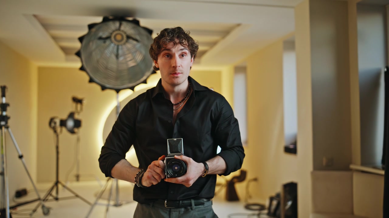Mann undersøker retro mellomformat filmkamera i studio. Fotograf i arbeid.
