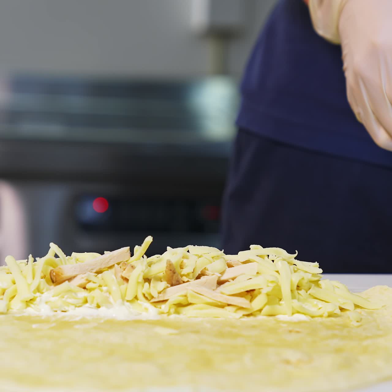Chef prepares pita bread. Professional cook is putting cheese and chopped cucumbers into pita. Fast food. Caucasian cuisine. Close-up