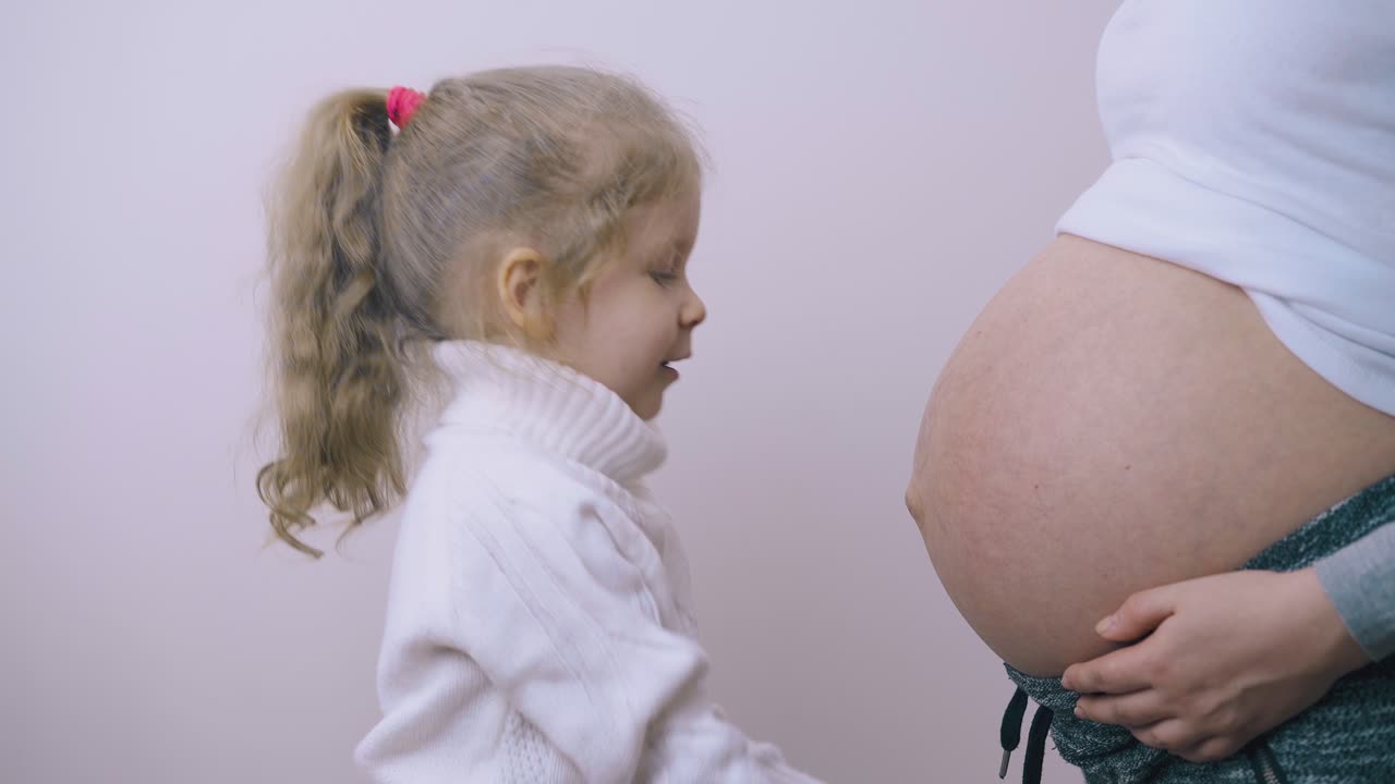 chica linda toca el vientre de la madre embarazada con botas azules