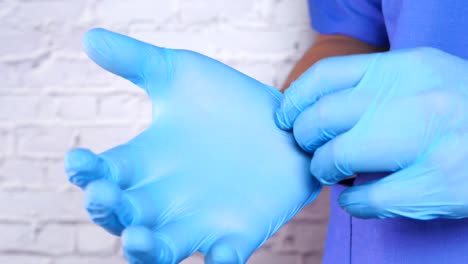 doctor putting on blue medical gloves