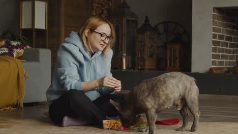 red haired woman caresses her bulldog dog while shi is sitting on the floor in the living room at home