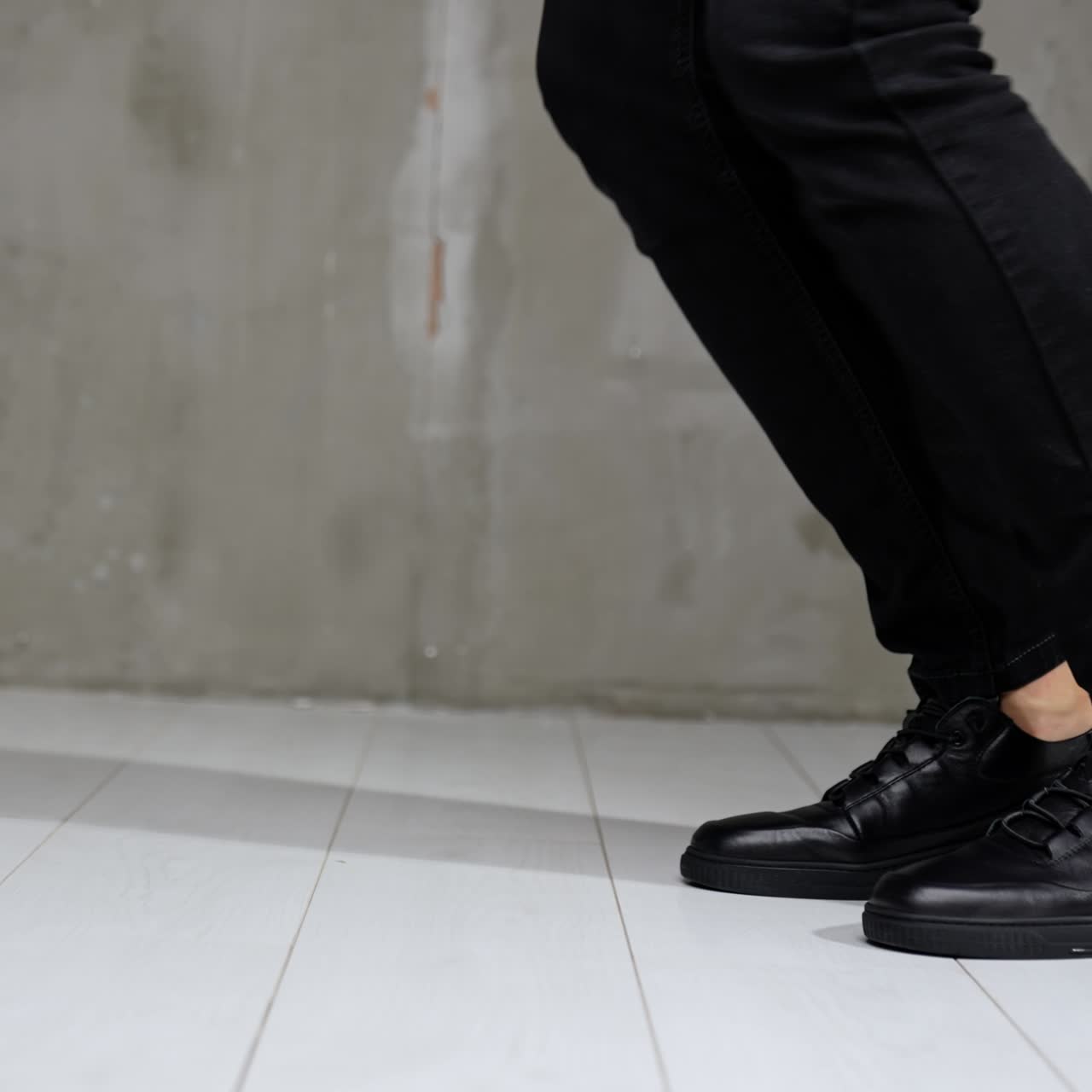 Unrecognized man in black jeans and leather sneakers showing moonwalk. Stylish male footwear demonstration in studio