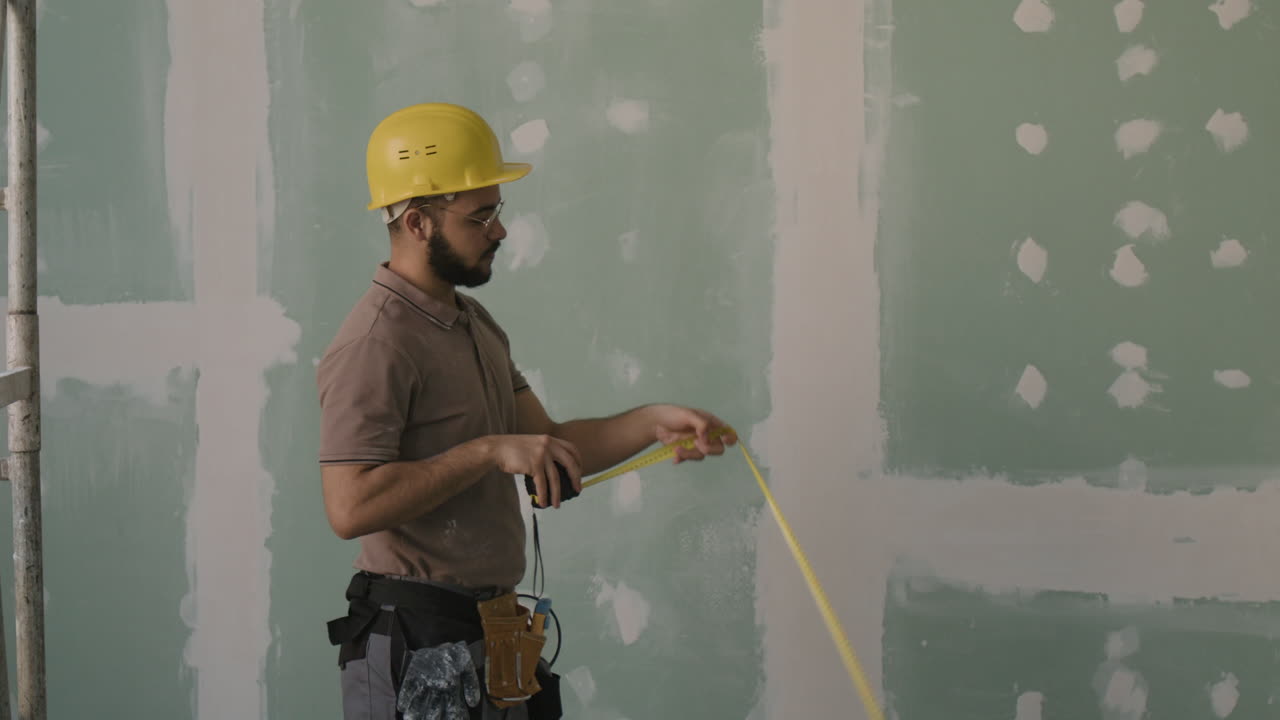 Construction worker measures drywall