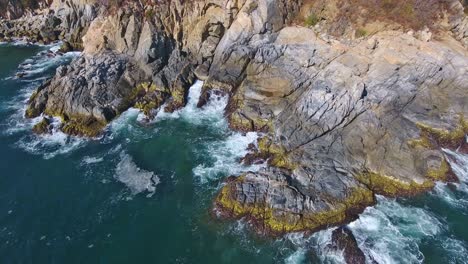 overhead hover of waves crashing on interesting coastal rock formations