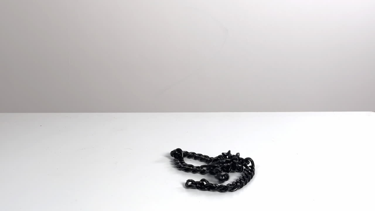 Black Chain Falling and Coiling on a White Surface