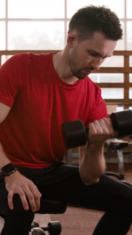 man doing bicep curls with a dumbbell in a gym