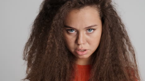 angry caucasian curly haired woman looking to the camera.