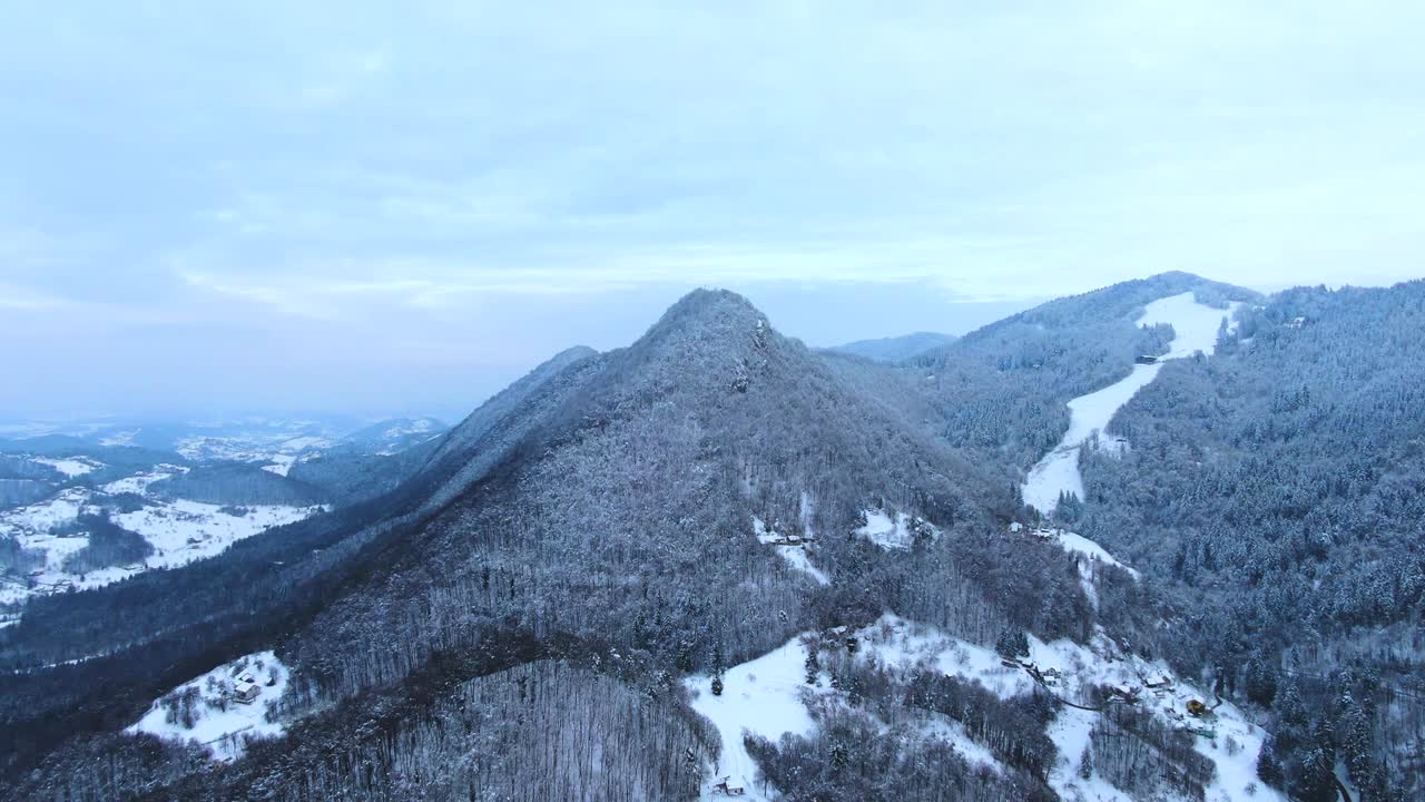 Long winding aerial drone clip over the snowed mountain tops of the Celje area in Slovenia