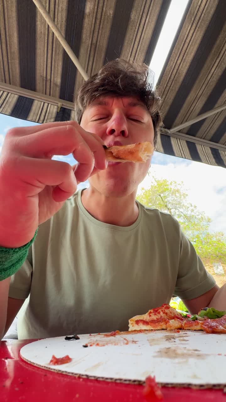 Person enjoying a pizza outdoors