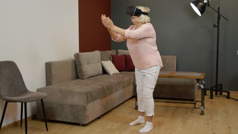 happy senior woman in virtual reality headset glasses, trying to touch something, watching 3d video