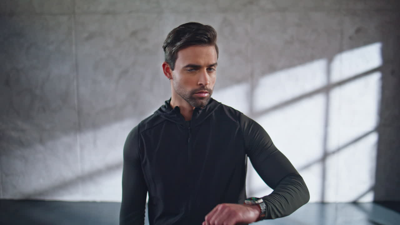 Atleta olhando para smartwatch em um quarto amplo, em close-up. Atleta rastreando resultado