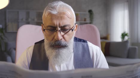 mature man reading newspaper at home.