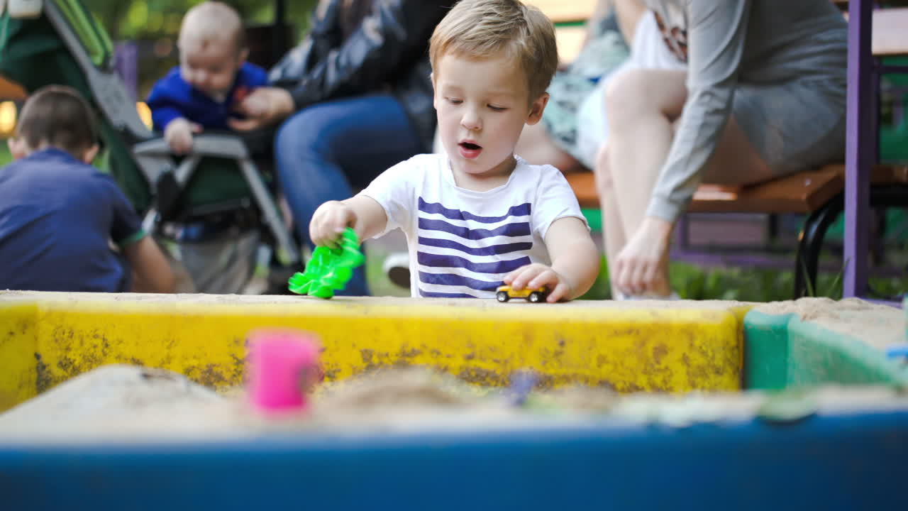 Child playing with toys in sand-pit