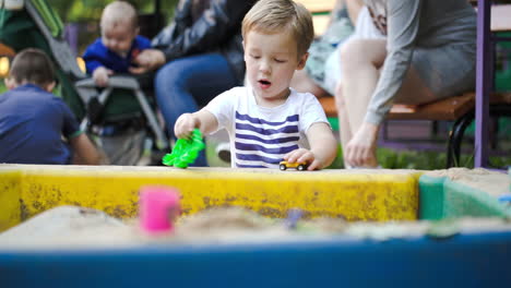 child playing with toys in sand-pit