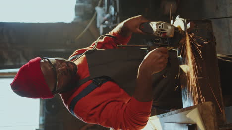 black man polishing metal detail with angle grinder in smithy