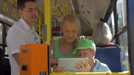 familia joven con niño usando almohadilla en el autobús