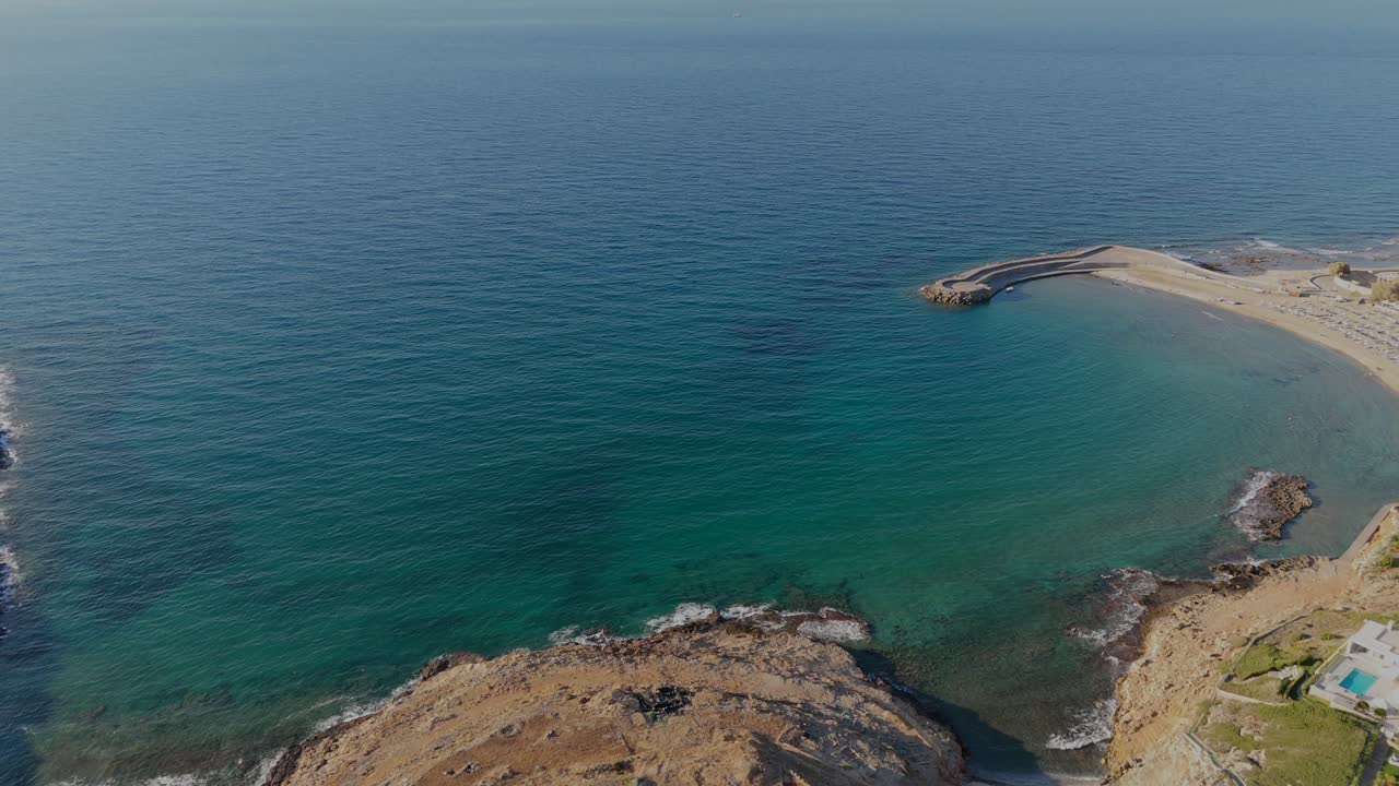 Aerial view of a rocky shoreline meeting the clear turquoise waters of Crete, Greece