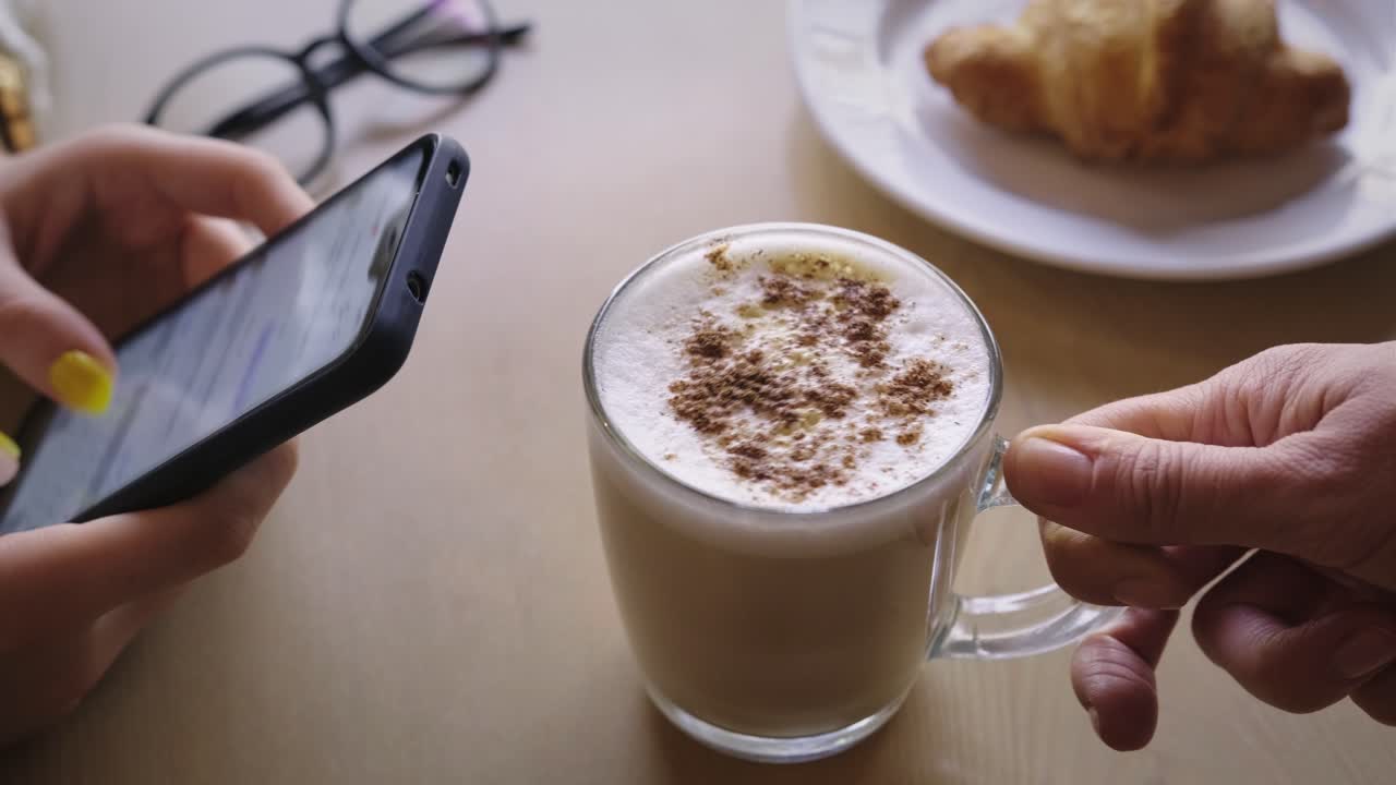 Woman using smartphone in a cafe having breakfast