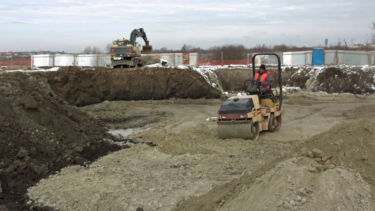 Construction site with road roller and excavator