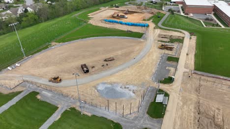 Construction-site-with-working-excavator-near-school-in-american-suburb