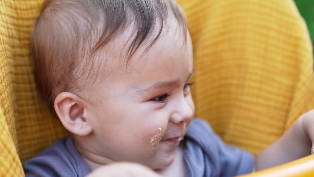 Adorable little toddler with smudgy face smiling cutely. Baby eating and laughing showing two lower teeth. Close up.
