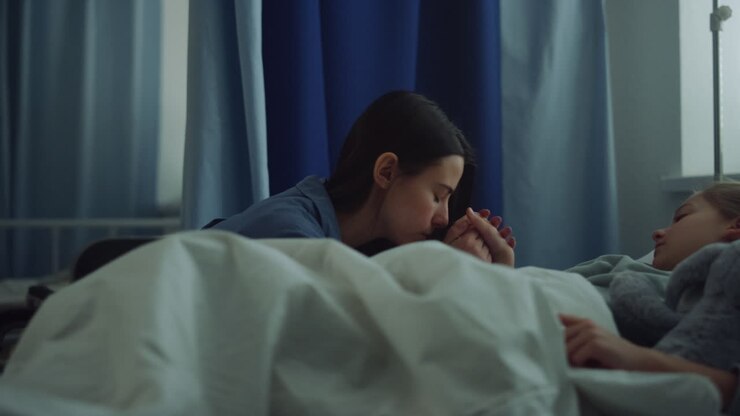 Mother sitting sick daughter after surgical treatment in modern hospital ward.