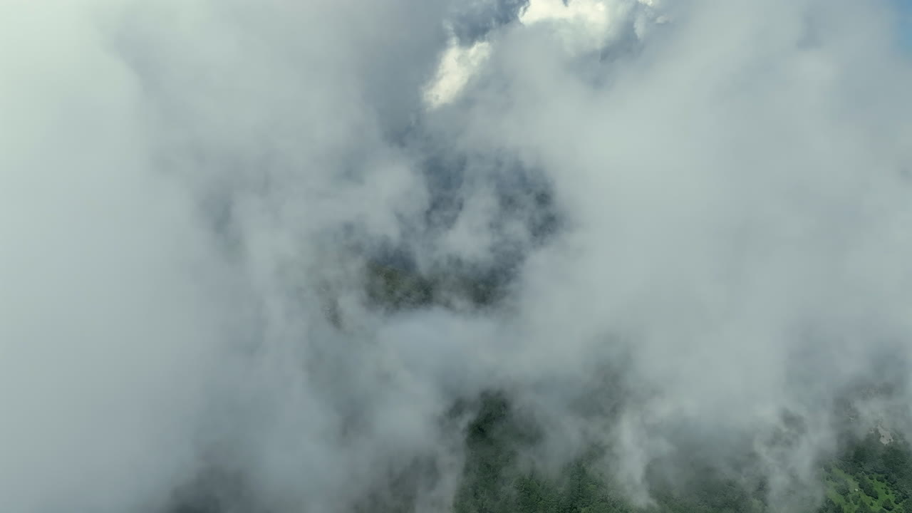 volando a través de nubes blancas y esponjosas por encima de los picos verdes de las montañas