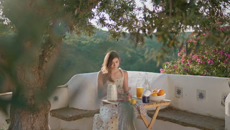 relaxed girl enjoying lunch at open air. romantic woman pouring juice at terrace