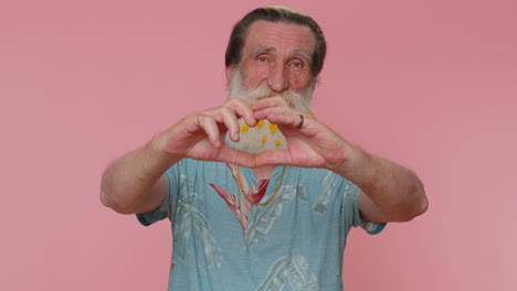 Smiling-senior-grandfather-man-makes-heart-gesture,-love-sign-expresses-good-feelings-and-sympathy