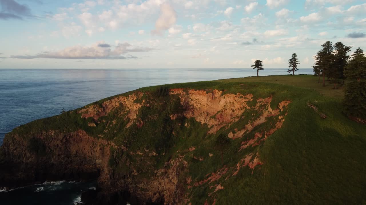 Ascending aerial shot of picturesque cliffs and rocks on the beautiful coast of norfolk island at golden hour overlooking the blue pacific ocean during an exciting journey through australia